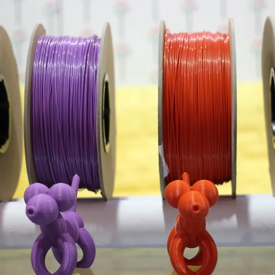 Purple and red filament spools beside the parts printed from them