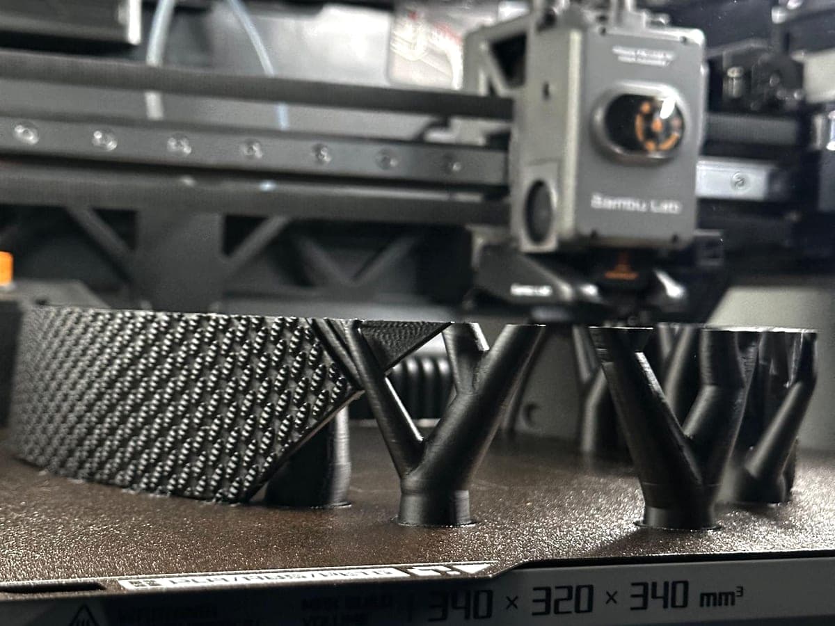 The toolhead moving over a black part being printed on tree supports