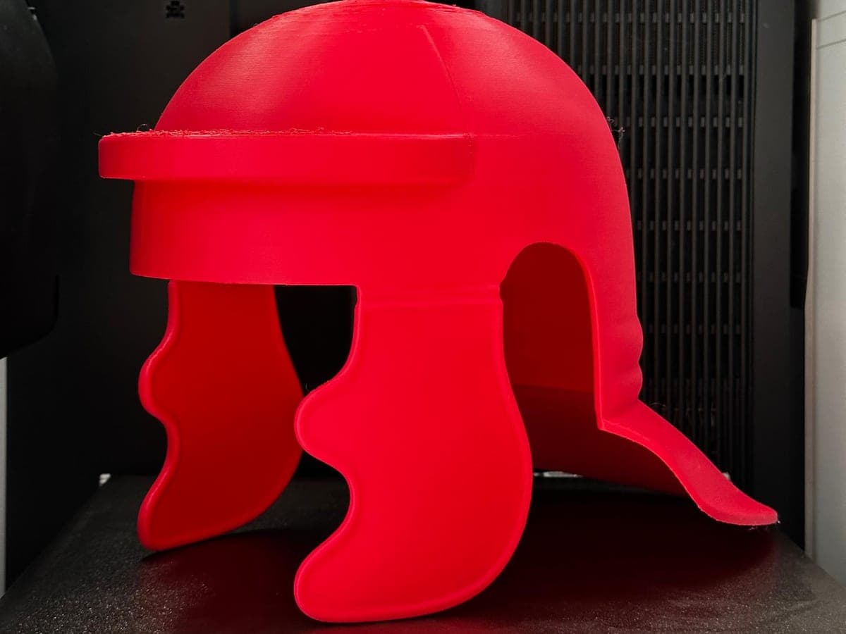 A red helmet printed in one piece, standing on the build plate